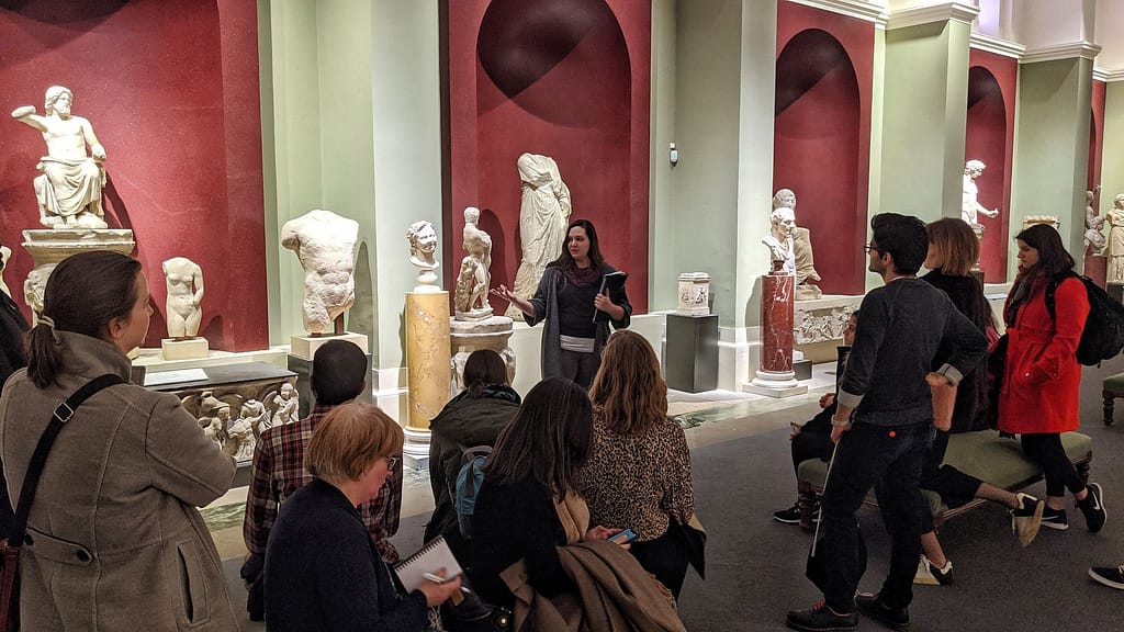 An Uncomfortable Oxford guide presents information to a tour group inside the Ashmolean Museum.