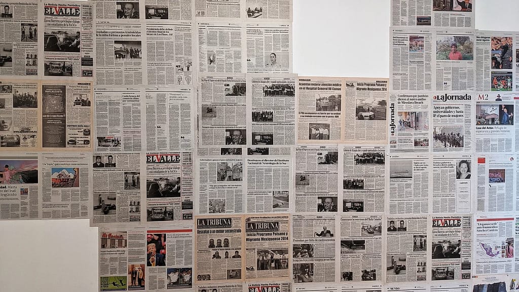 Collage of Spanish-language newspapers on a wall. 
