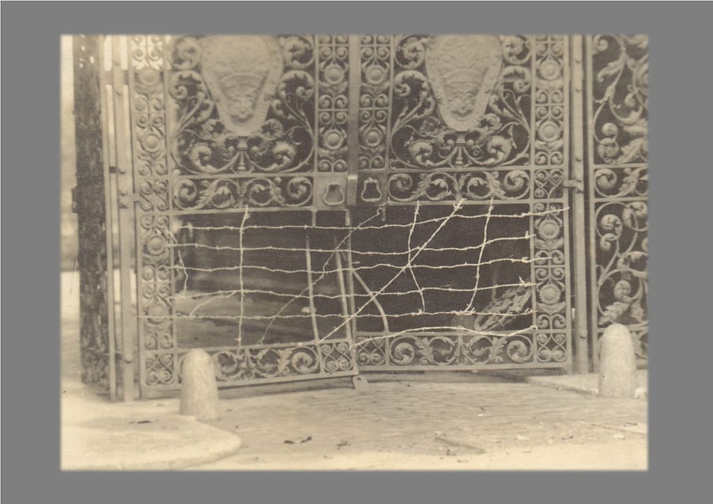 Black and white archive photograph of a damaged iron gate. 