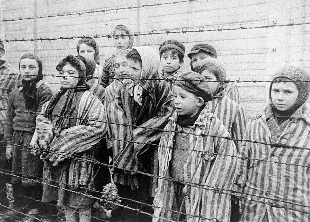 Children with striped shirts behind barbed wires. 