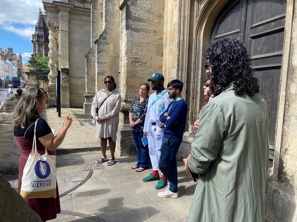 An Uncomfortable Oxford Guide gives a tour to a crowd of people.