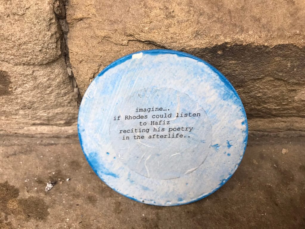 Blue plate painted in white with a quote printed in black, set against a wall