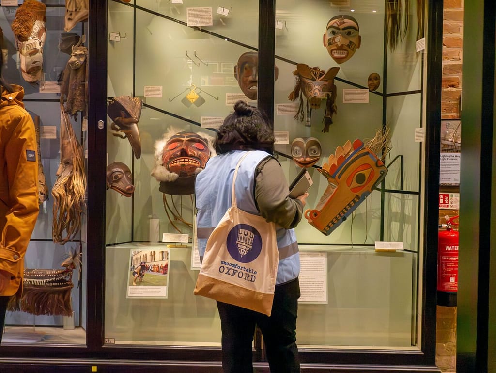 An Uncomfortable Oxford Tour guide stands inside the Pitt Rivers Museum.