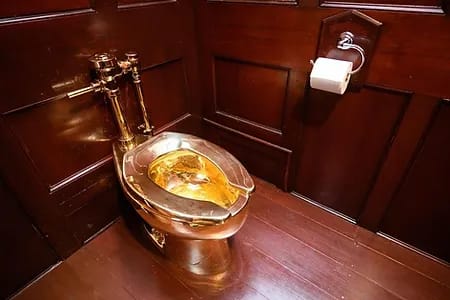 A golden toilet gleams in a wood paneled room.