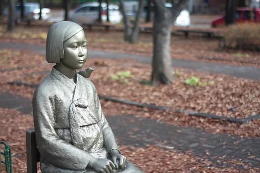 The Sonyeosang, or statue of girl, sits with her hands clenched as she gazes at the Japanese Embassy in Seoul.