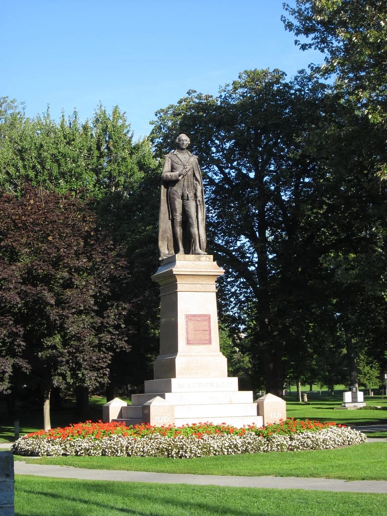A statue of a man wearing a cape in a garden.