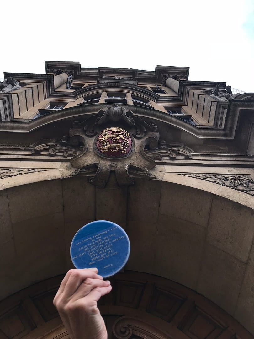 Hand holding a blue plaque into an archway