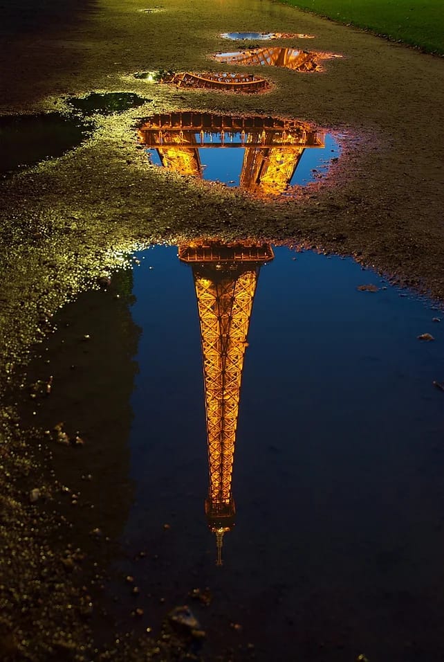 Reflection of the Eiffel Tower in a water puddle.