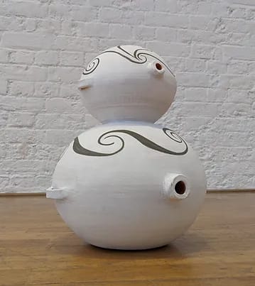 Two part round ceramic vase or container on the floor. 