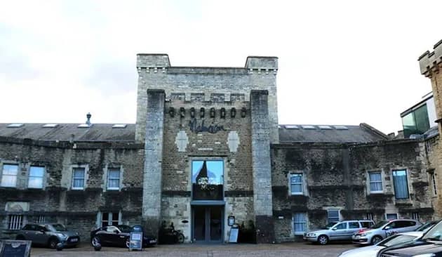 Photo of the entrance to a castle or medievale tower with cars parked at the front. 