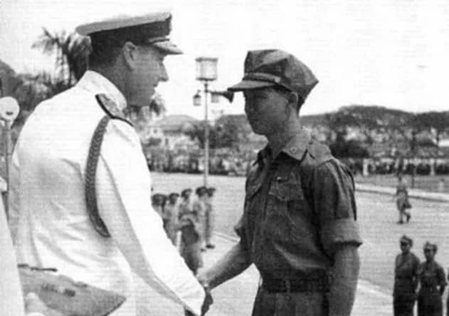 A man in ceremonial white uniform shaking the hand of a man in a military uniform. 