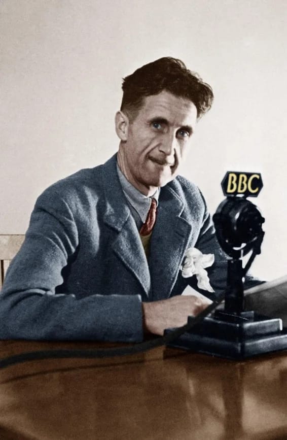 Photograph of a man in suit sat next to a radio mic.